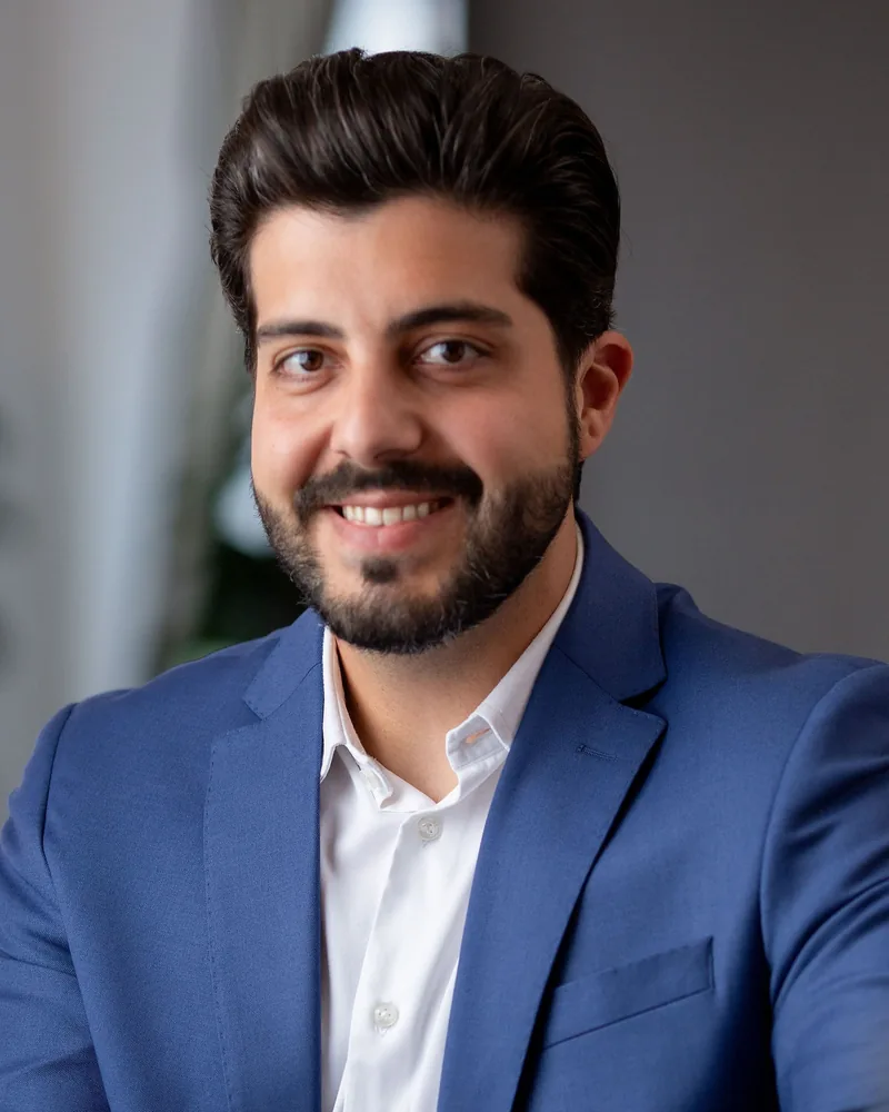 Retrato do Dr. Renan Gerbelli Canever, médico ortopedista, de blazer azul e camisa branca, sorrindo
